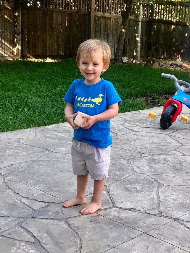 Happy Toddler boy wearing blue and yellow Boston Ducklings t-shirt