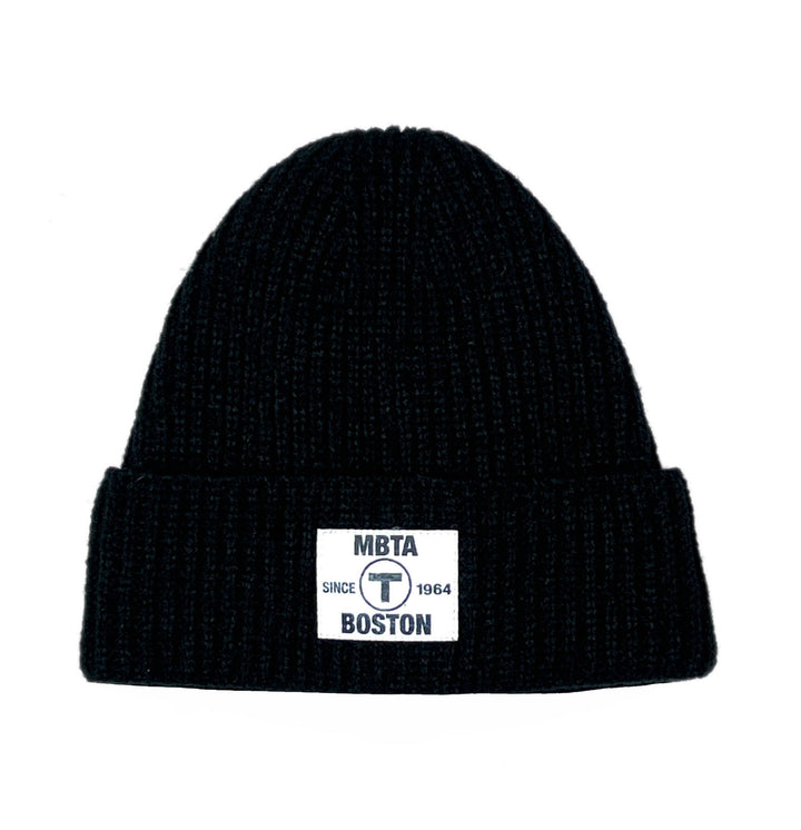 Black beanie hat with off white rectangular woven patch containing the MBTA logo