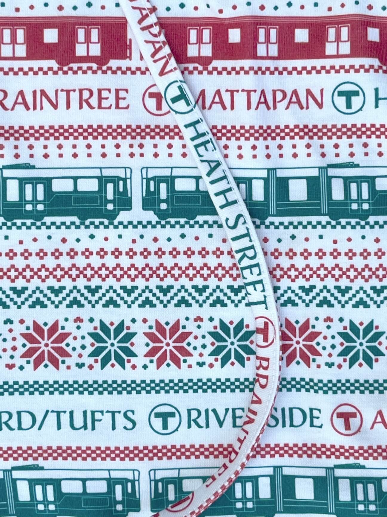 A close-up of ivory-colored MBTA-themed pajama bottoms with Red Line trains and Green Line trolleys, T Logos and MBTA destination station names.
