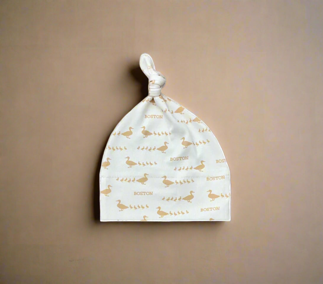 Ivory colored knit baby hat with golden brown Boston ducklings pattern