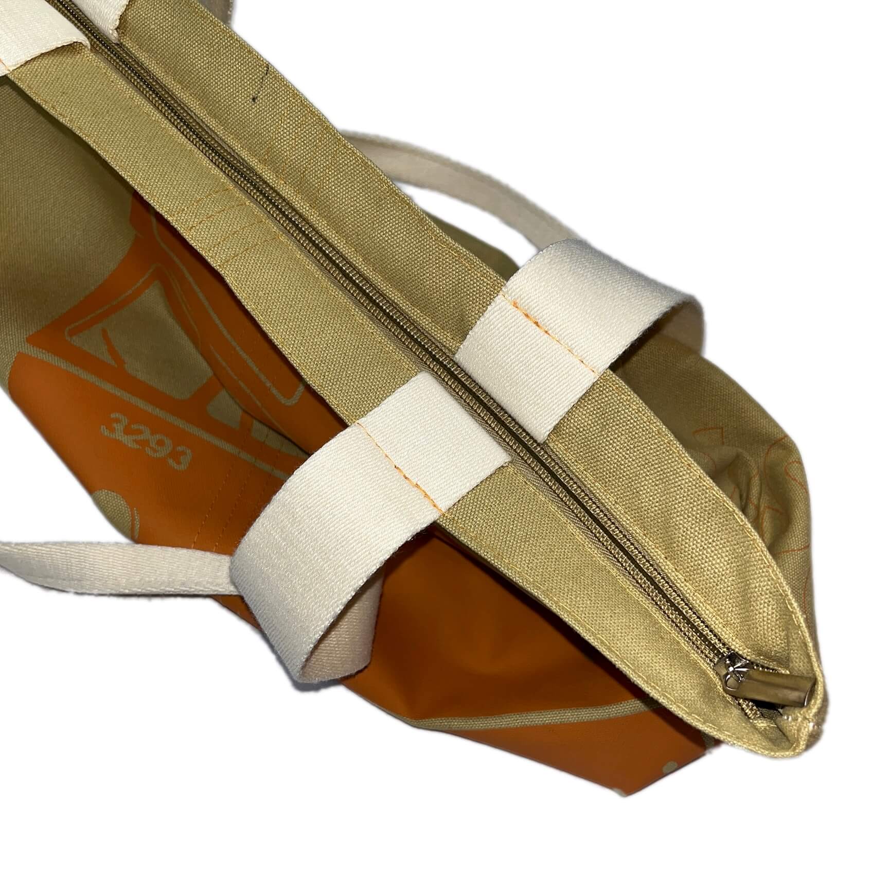 Tan canvas tote bag with large orange Boston MBTA PCC bus graphic and zipper closure