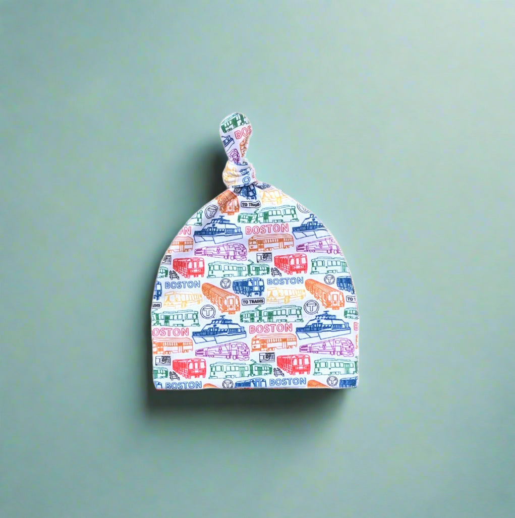 White soft cotton knit newborn baby hat with colorful MBTA vehicles pattern