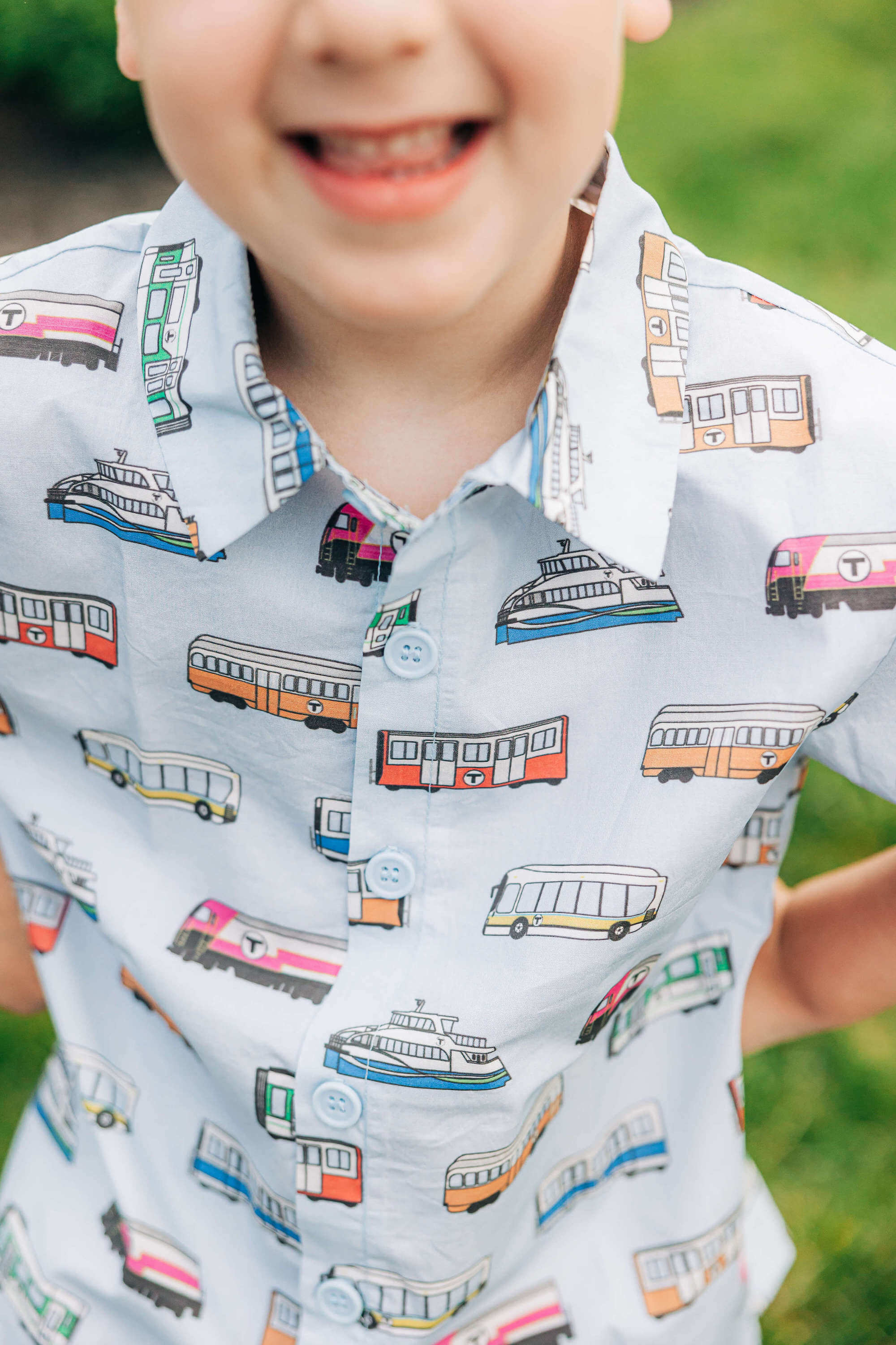 Toddler boy wearing light blue short sleeve woven shirt with MBTA trains and buses print