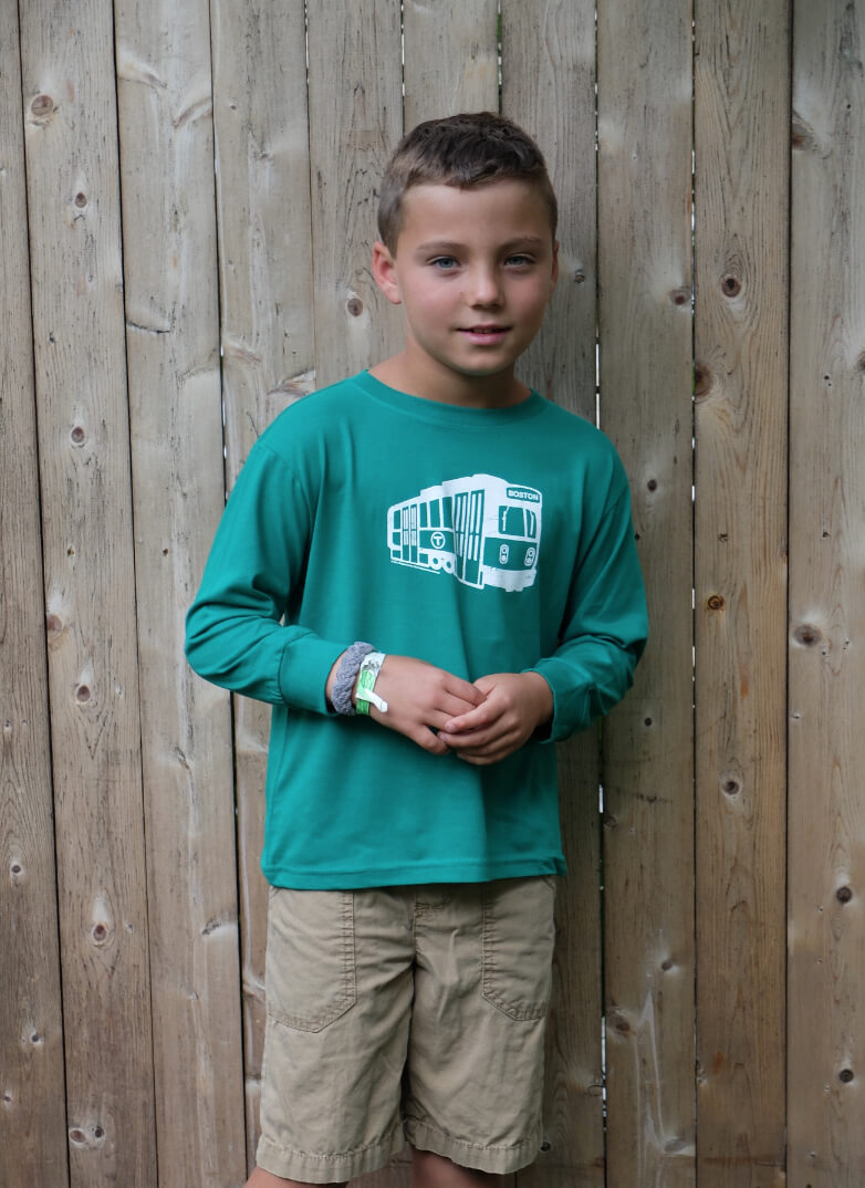 Boy wearing green long sleeve t-shirt with white Boston MBTA subway trolley graphic