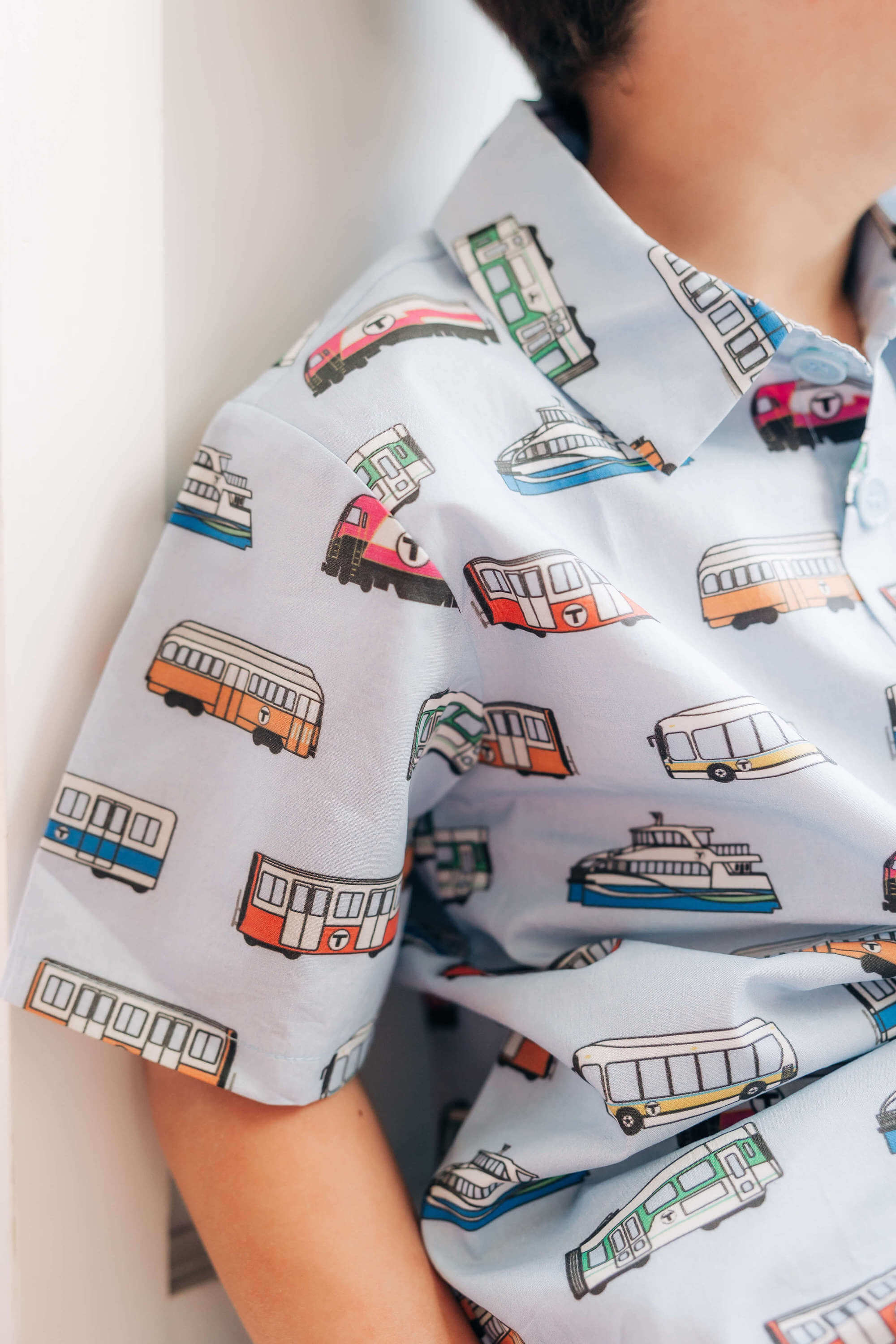 Boy wearing light blue party shirt with Boston MBTA vehicles print